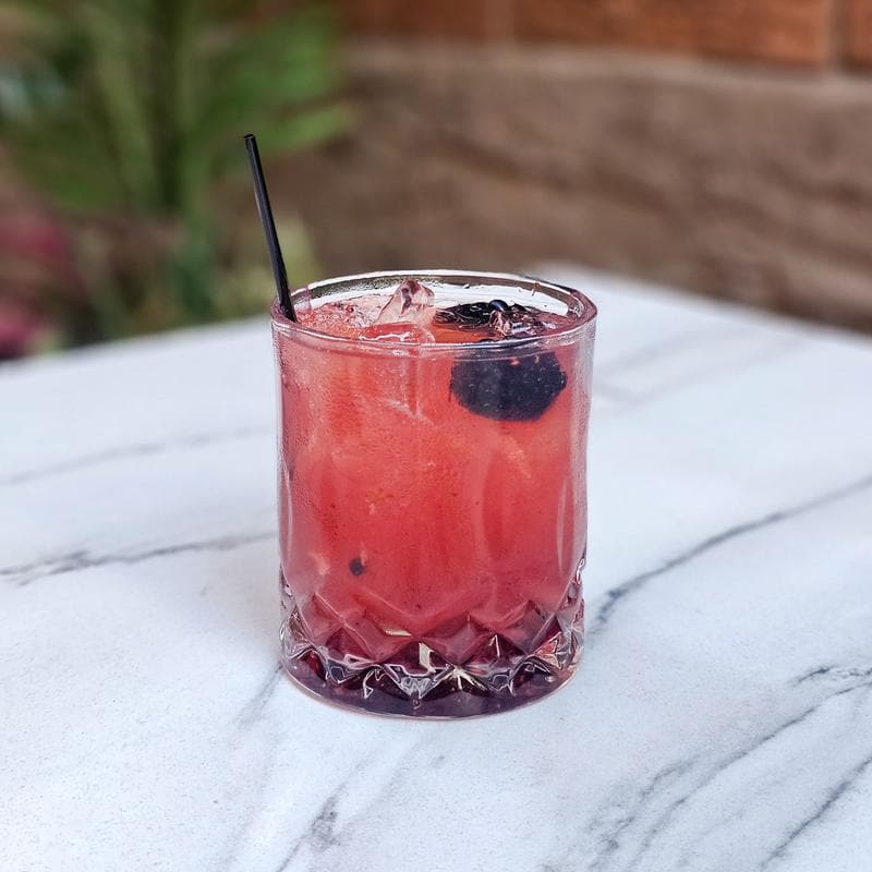 Kentucky Bash cocktail with blackberry garnish on a marble table