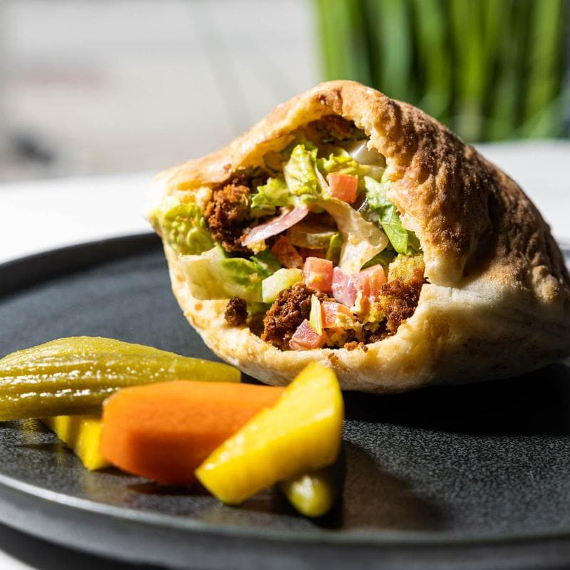 Stuffed pita with falafel, lettuce, tomato, pickles, and red onion